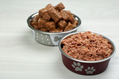 Different pet food in feeding bowls on white wooden background