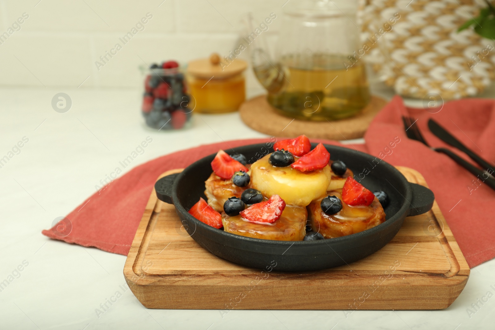 Photo of Delicious cottage cheese pancakes with fresh berries and honey served on white table