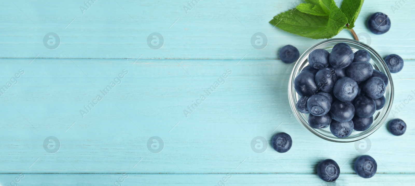 Image of Tasty fresh blueberries on turquoise wooden table, flat lay with space for text. Banner design