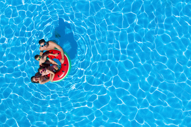 Image of  Happy family with inflatable ring in swimming pool, top view. Space for text