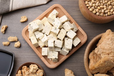 Photo of Pieces of delicious tofu and other soy products on wooden table, flat lay