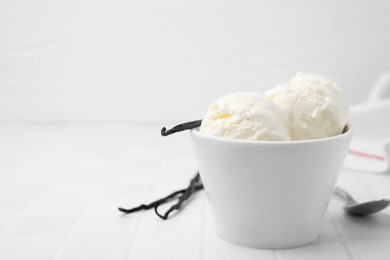 Photo of Delicious vanilla ice cream in bowl on white tiled table, closeup. Space for text