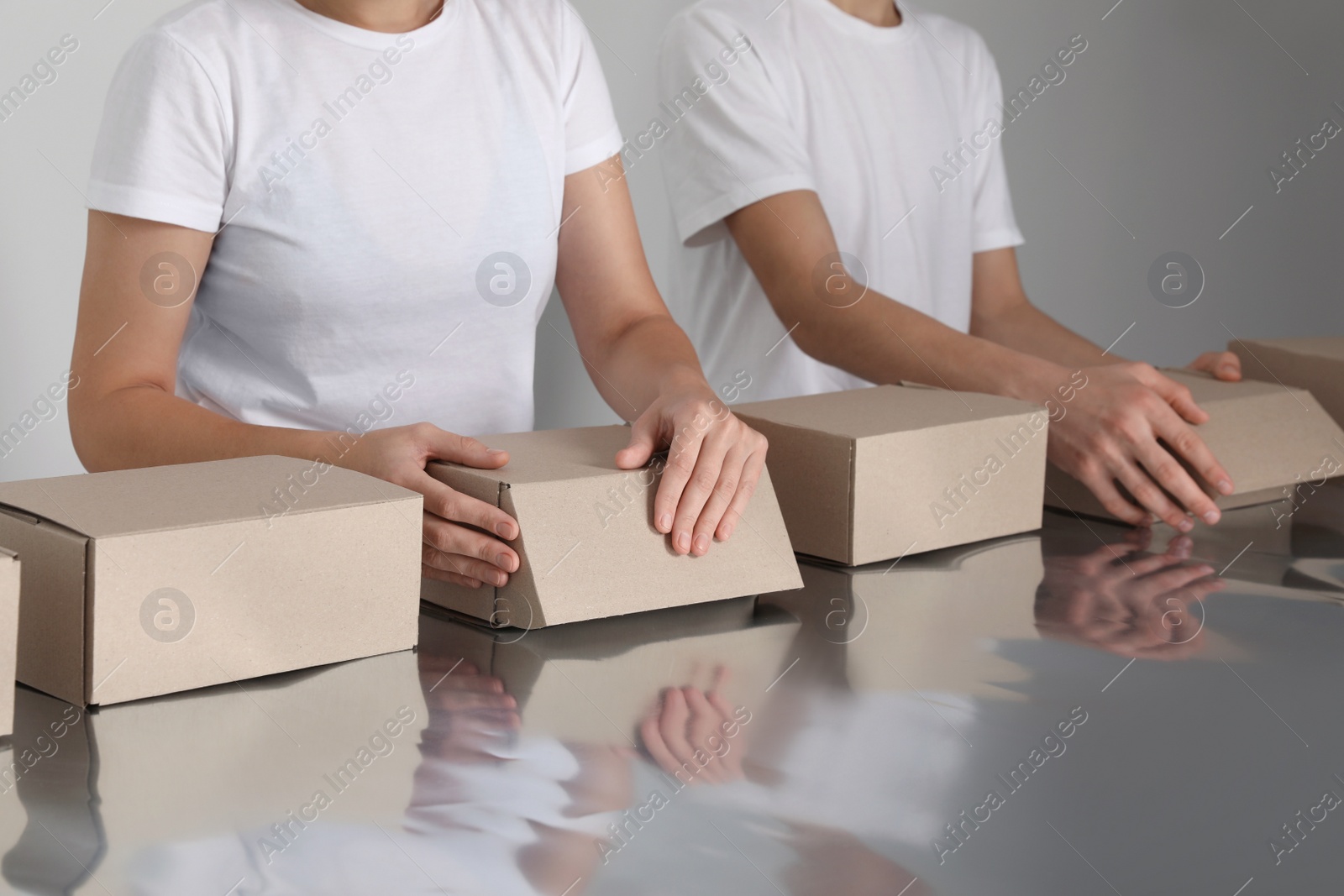 Photo of Workers folding cardboard boxes at table, closeup. Production line 