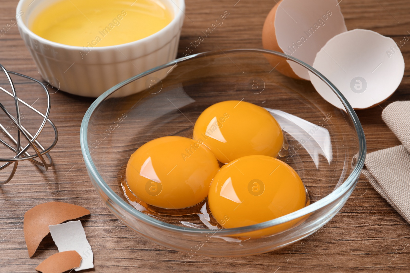 Photo of Bowls with raw egg yolks on wooden table, closeup