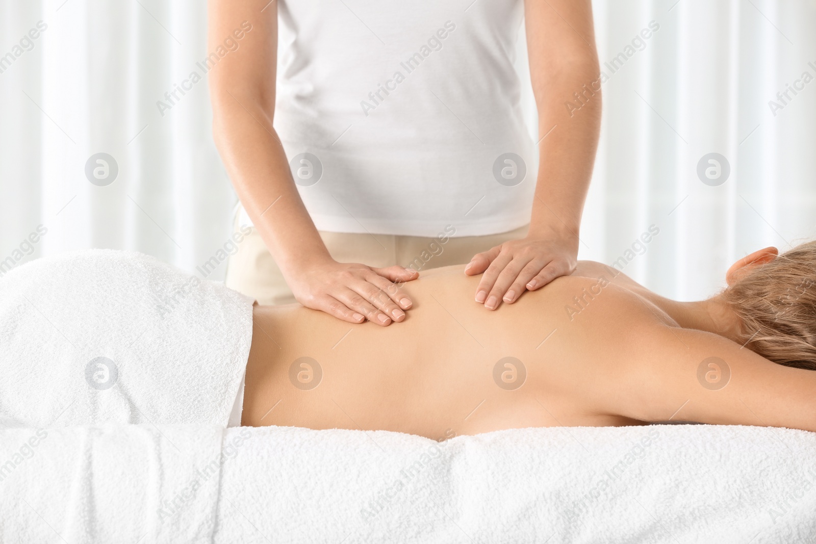 Photo of Relaxed woman receiving back massage in wellness center