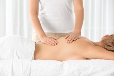 Photo of Relaxed woman receiving back massage in wellness center