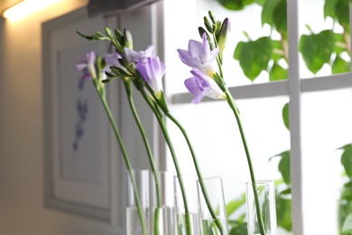 Photo of Beautiful freesia flowers near window in kitchen, closeup