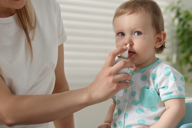 Photo of Mother helping her baby to use nasal spray indoors