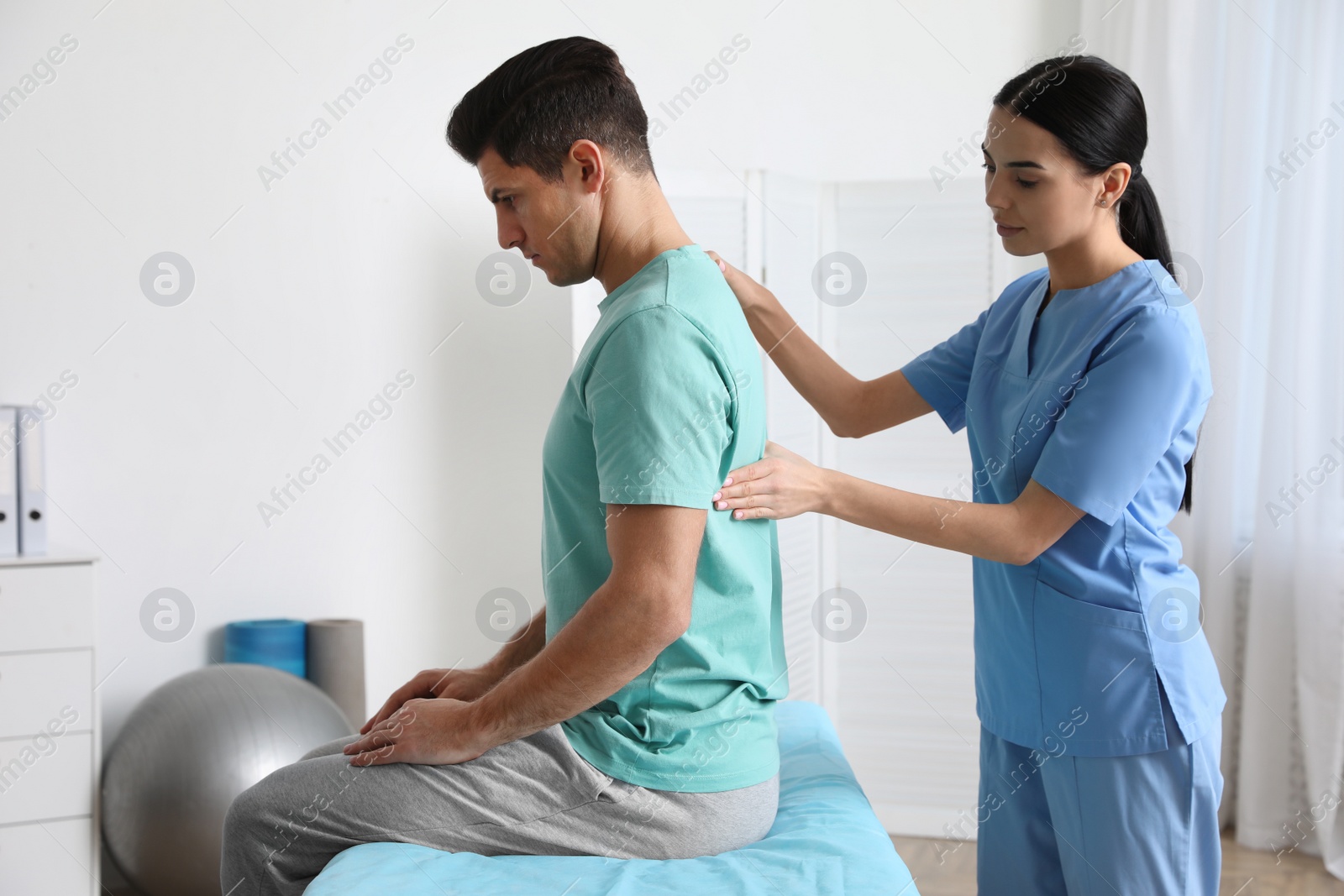 Photo of Orthopedist examining man's back in clinic. Scoliosis treatment