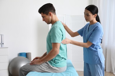 Photo of Orthopedist examining man's back in clinic. Scoliosis treatment