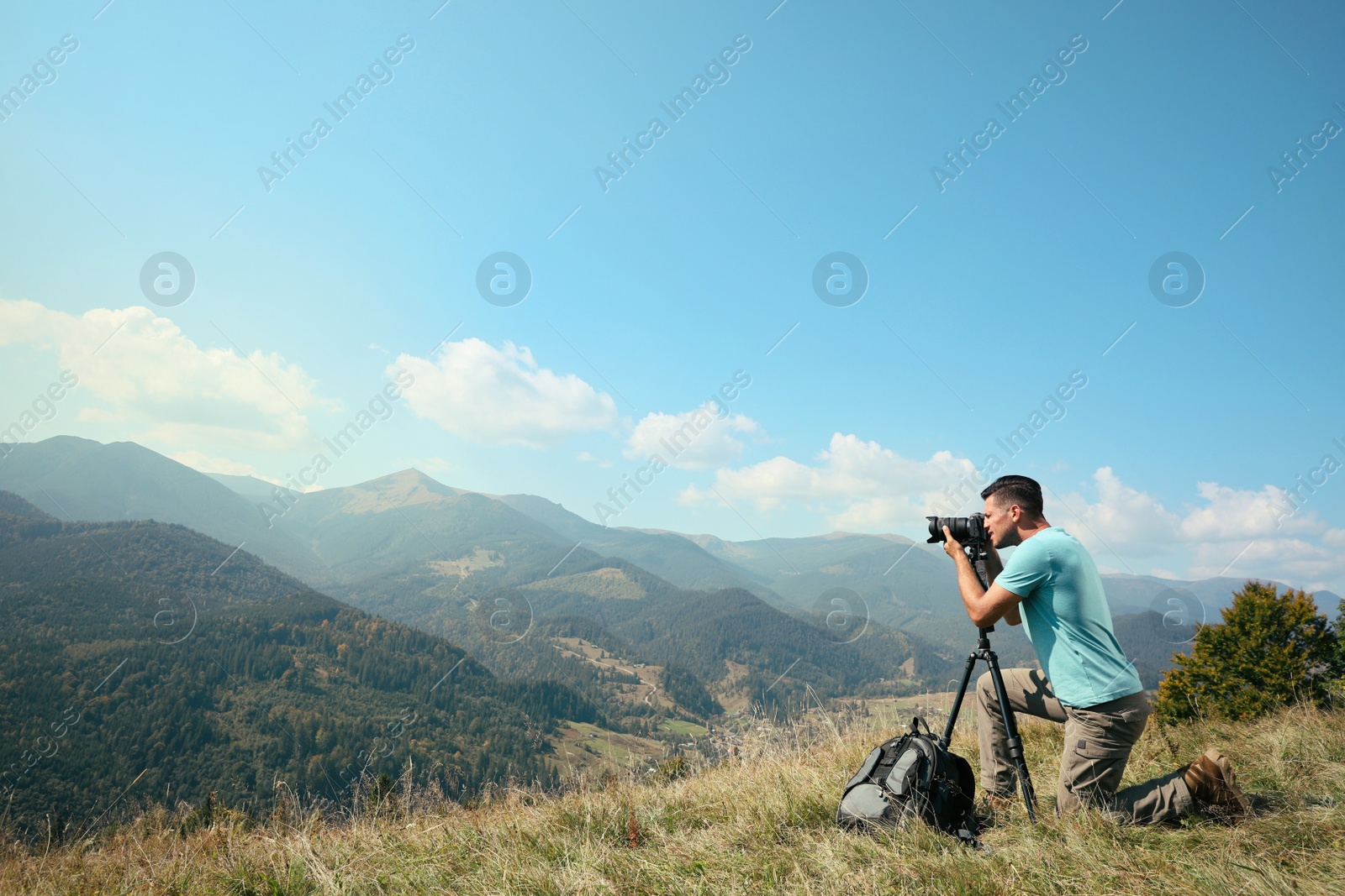 Photo of Professional photographer taking picture with modern camera in mountains. Space for text