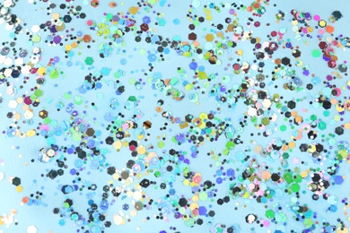 Photo of Shiny glitter on light blue background, top view