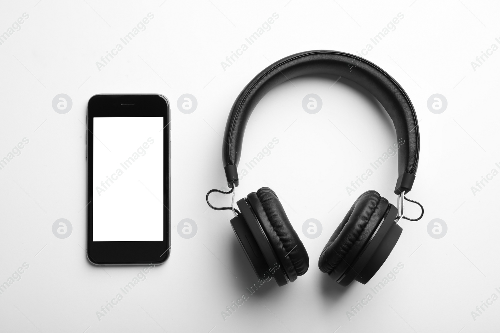 Photo of Stylish headphones and modern phone on white background, top view. Space for text