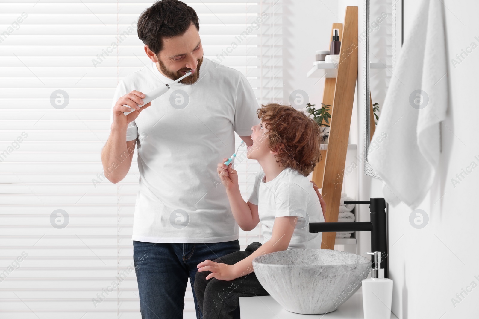 Photo of Father and his son brushing teeth together in bathroom