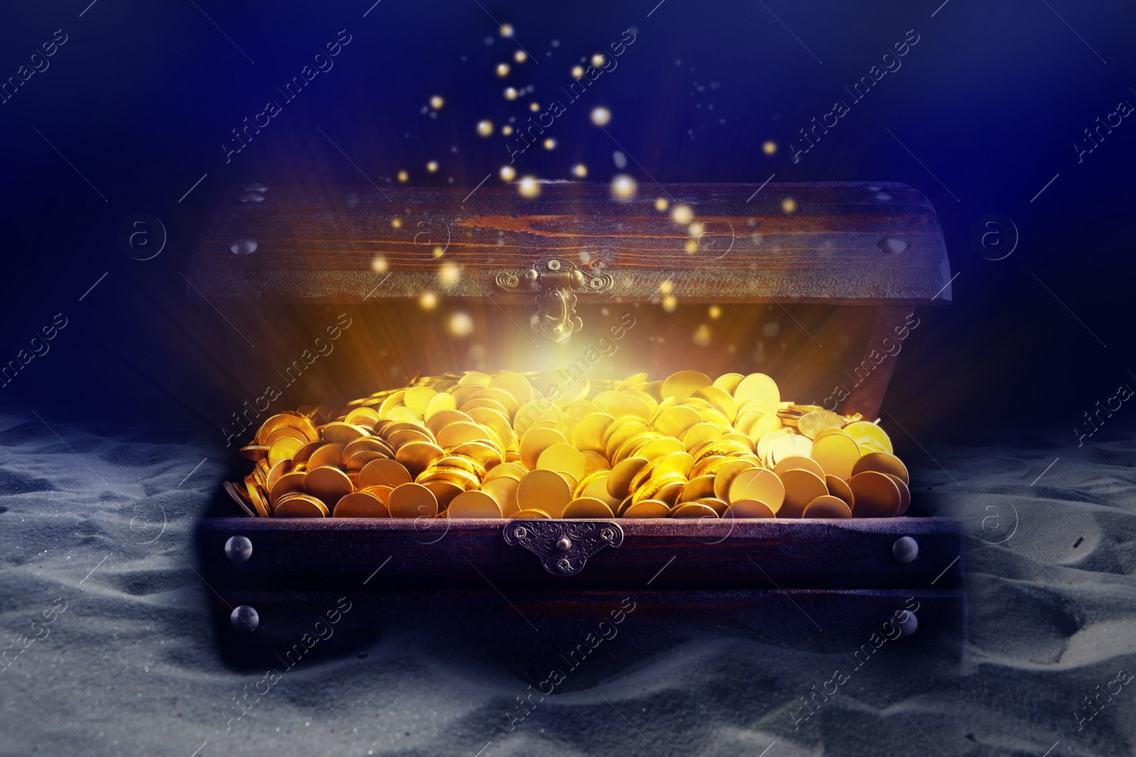 Image of Open treasure chest with gold coins on sand seabed