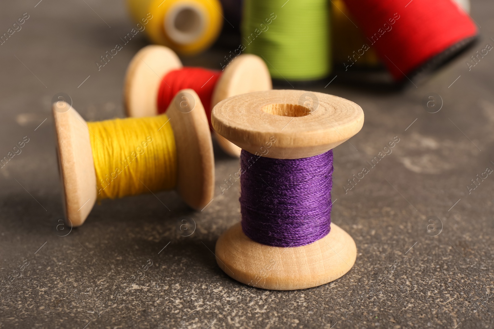 Photo of Set of color sewing threads on grey table, closeup