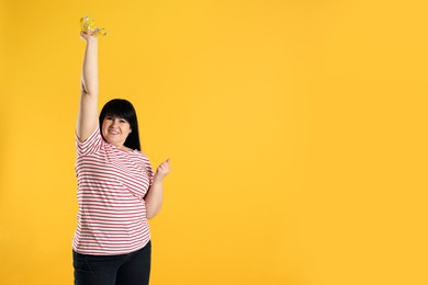 Photo of Happy overweight mature woman with measuring tape on orange background, space for text