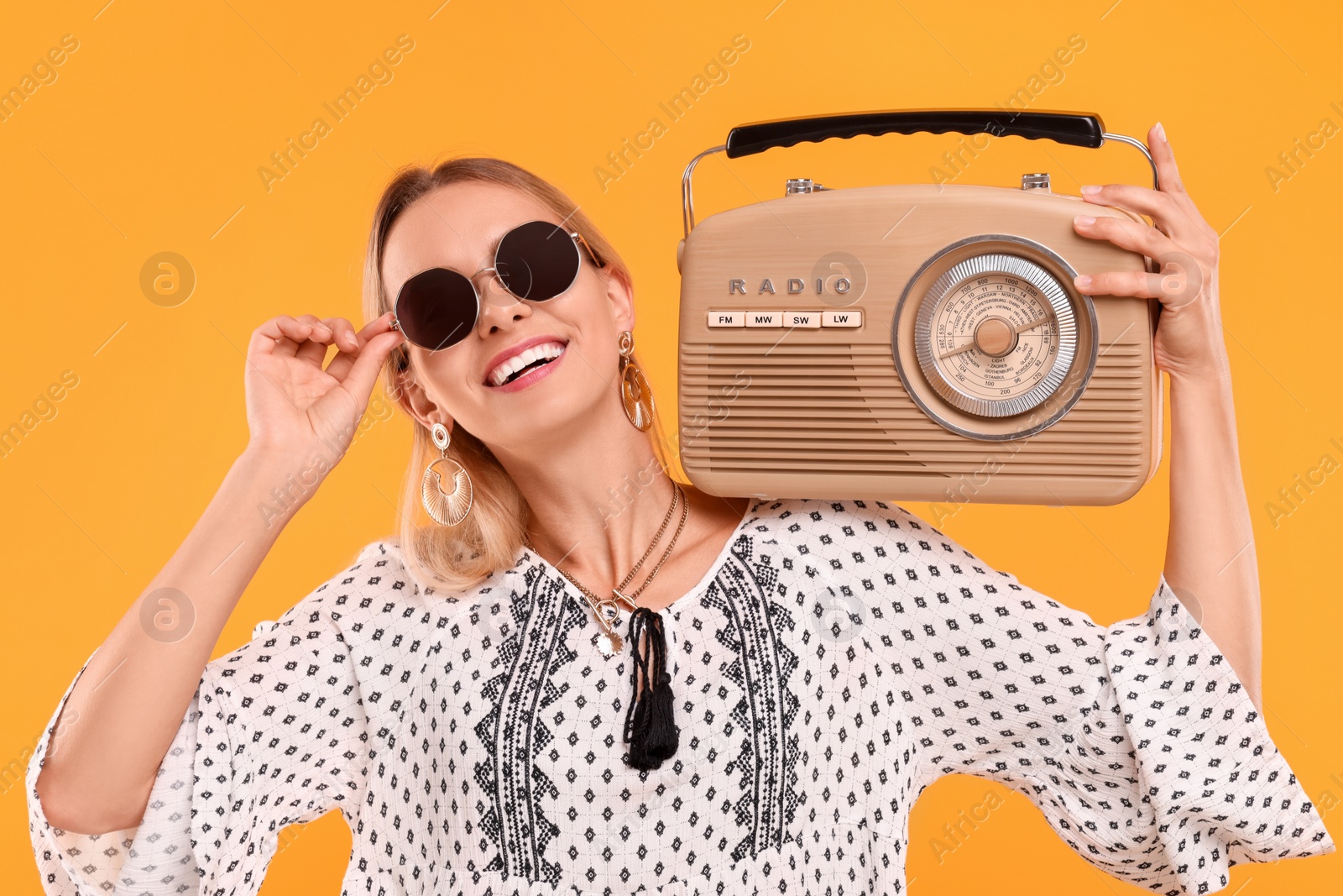 Photo of Portrait of happy hippie woman with retro radio receiver on yellow background