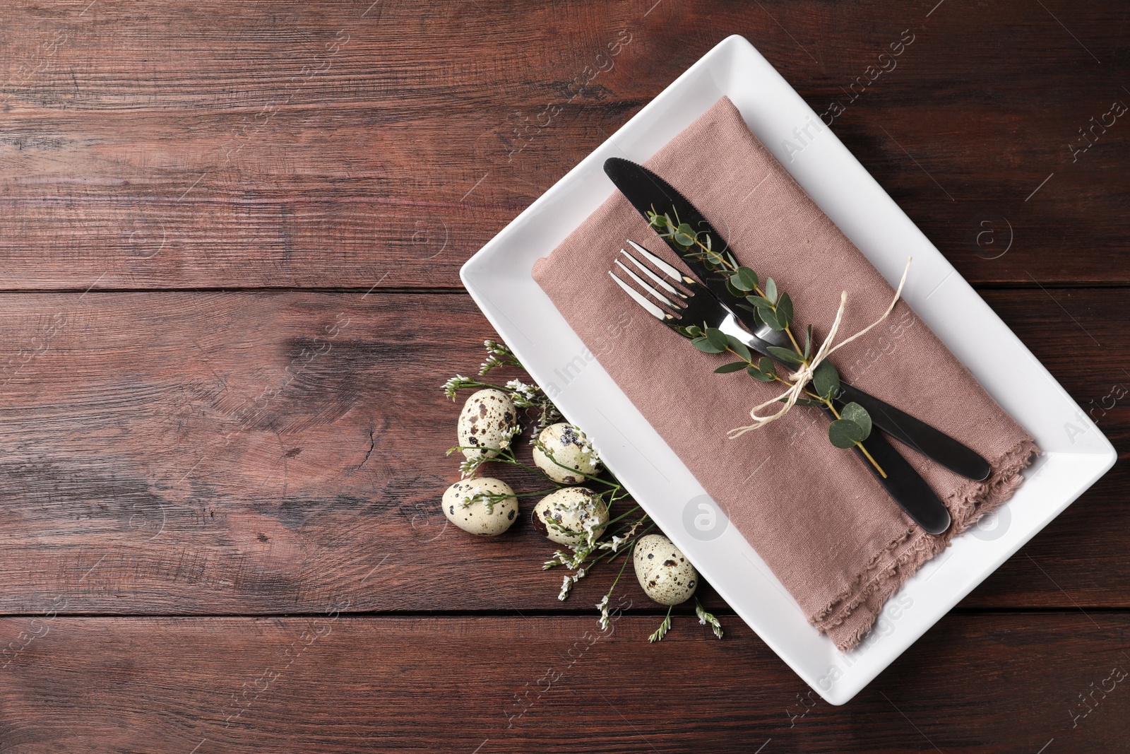 Photo of Festive Easter table setting with quail eggs and floral decor on wooden background, flat lay. Space for text