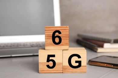 Photo of 5G and 6G technology, Internet concept. Wooden cubes on light office table, closeup