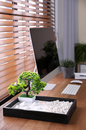 Photo of Modern workplace with beautiful miniature zen garden and computer in room