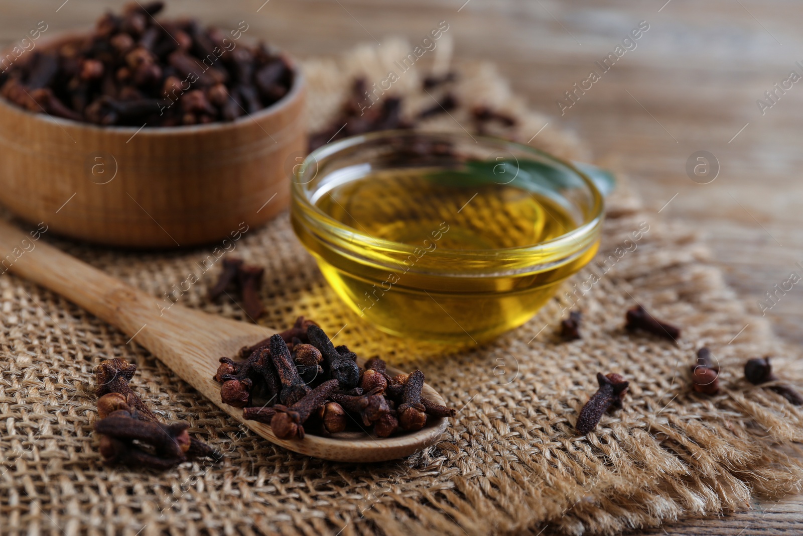 Photo of Essential oil and dried cloves on wooden table, closeup