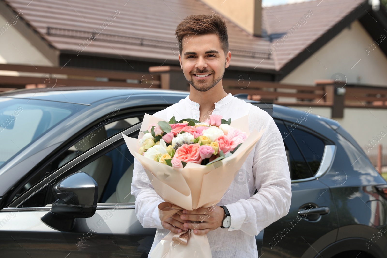 Photo of Young handsome man with beautiful flower bouquet near car outdoors