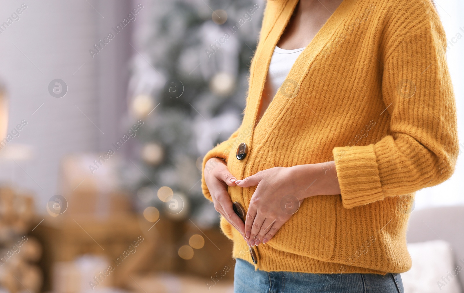 Photo of Young pregnant woman in room decorated for Christmas, closeup. Space for text