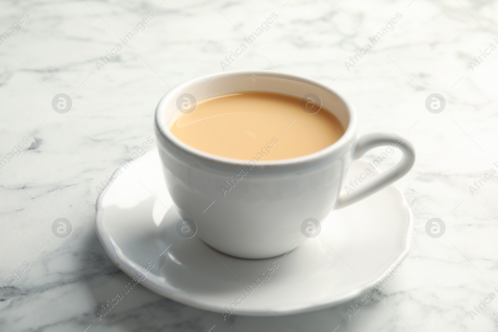 Photo of Cup with black tea and milk on marble table