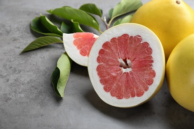 Photo of Fresh cut and whole pomelo fruits on grey table, closeup