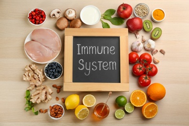 Chalkboard with phrase Immune System and fresh products on wooden table, flat lay