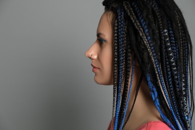Photo of Beautiful young woman with nose piercing and dreadlocks on grey background. Space for text