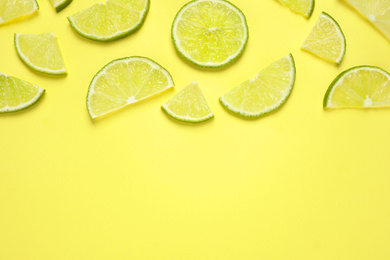 Photo of Juicy fresh lime slices on yellow background, flat lay. Space for text