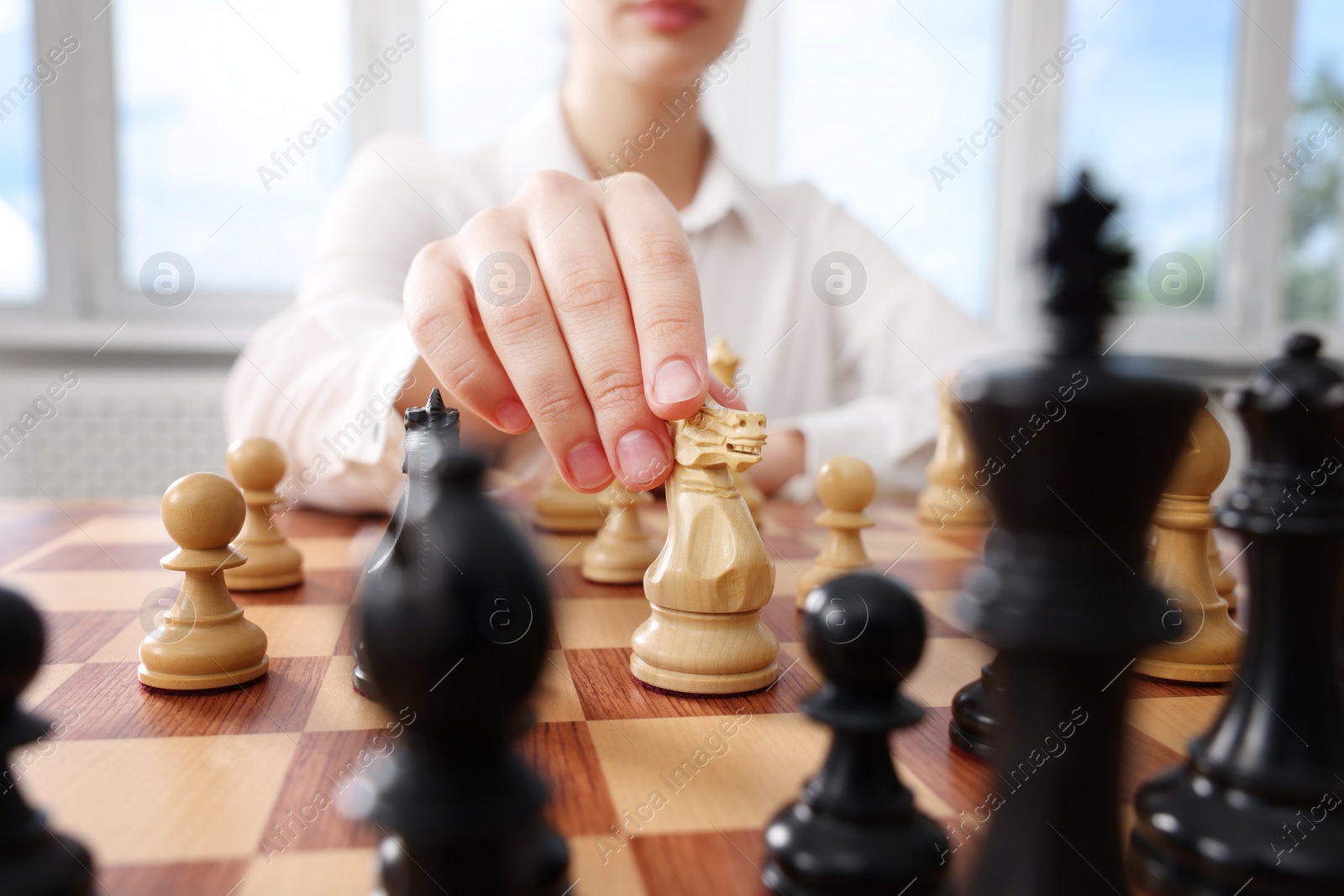 Photo of Woman playing chess during tournament at chessboard indoors, closeup