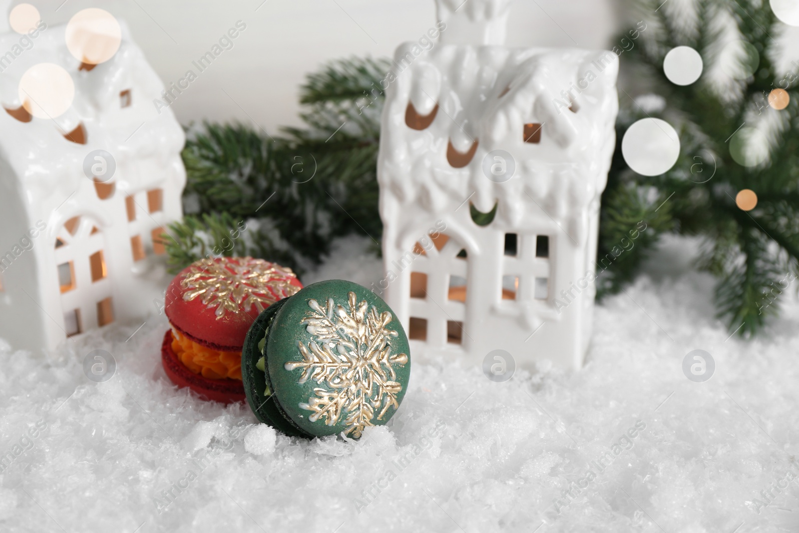 Photo of Different decorated Christmas macarons on table with artificial snow, space for text