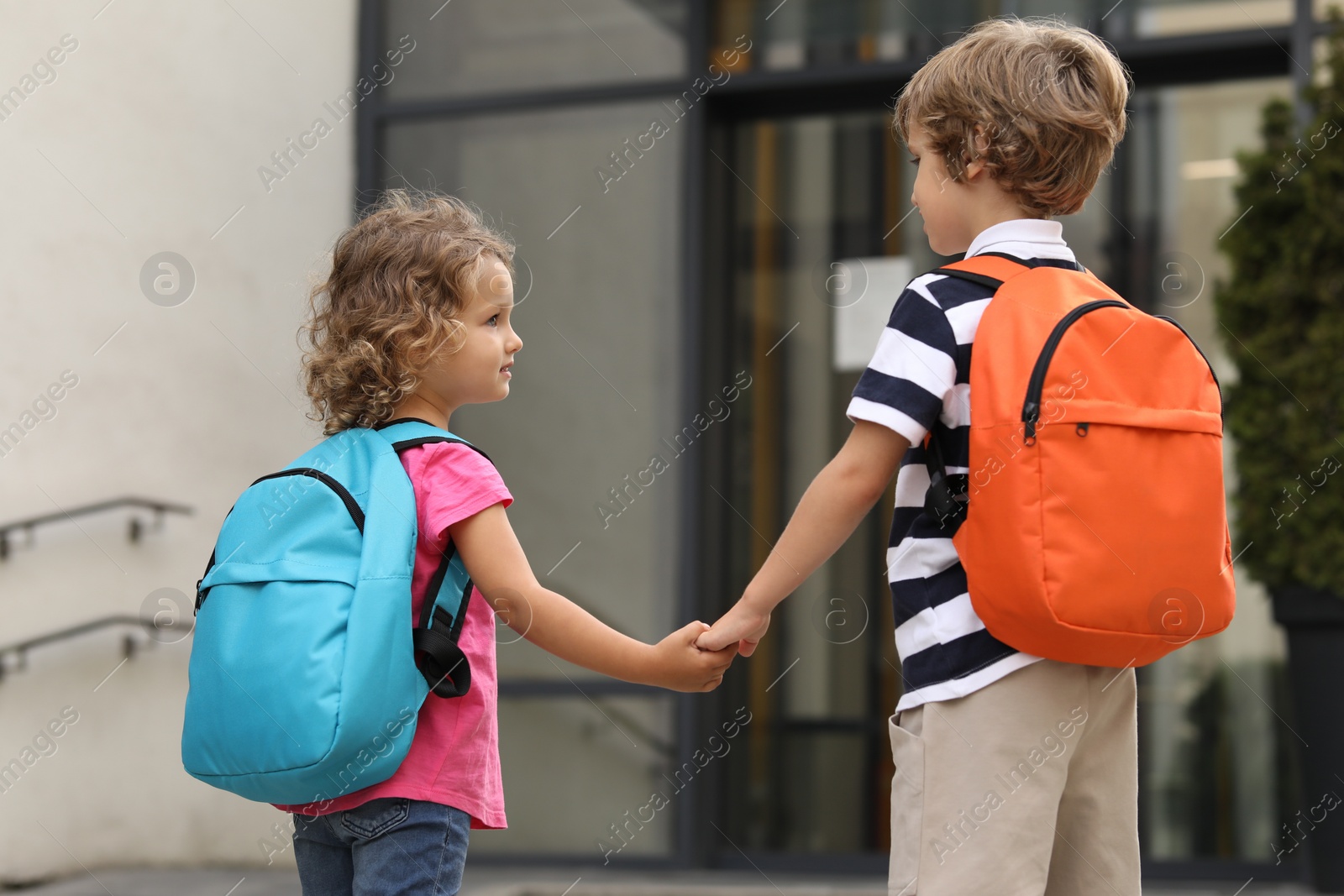 Photo of Brother and sister walking to kindergarten outdoors, back view