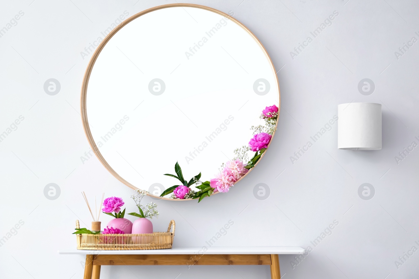 Photo of Round mirror and table with accessories near white wall in modern room interior