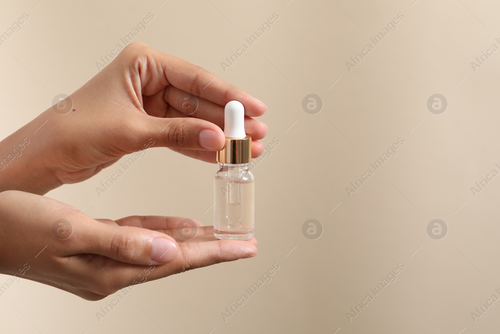 Photo of Woman with bottle of cosmetic serum on beige background, closeup. Space for text