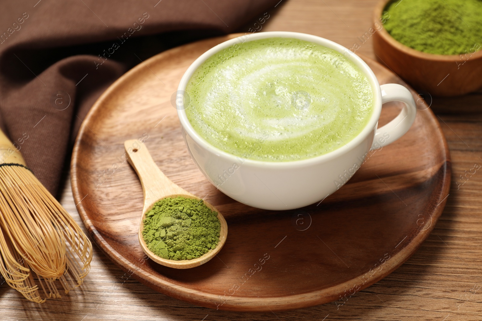 Photo of Cup of fresh matcha latte and powder on wooden table