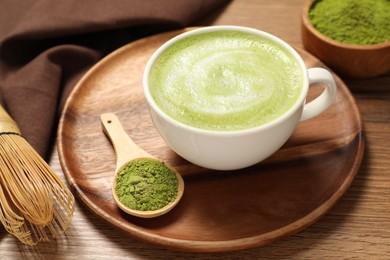 Photo of Cup of fresh matcha latte and powder on wooden table
