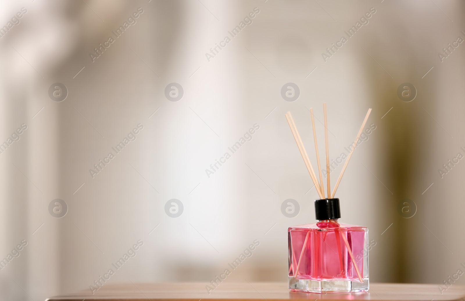 Photo of Aromatic reed air freshener on table against blurred background