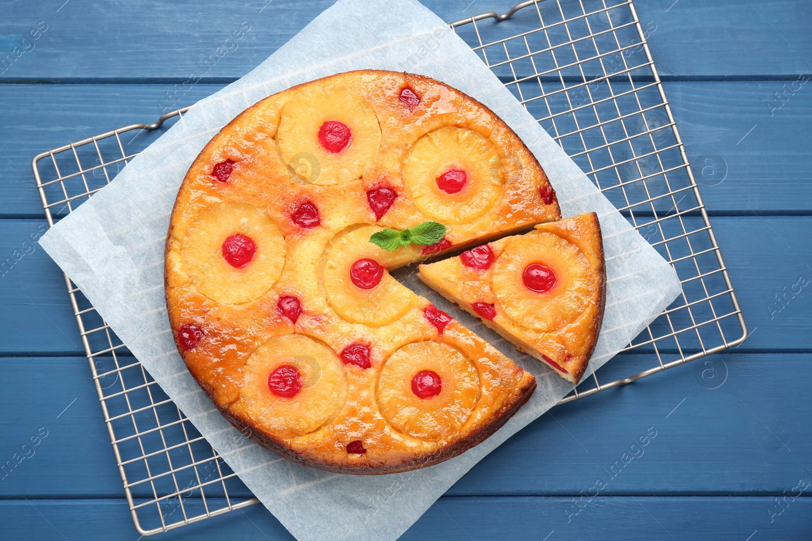 Photo of Delicious cut pineapple pie with cherry on blue wooden table, top view