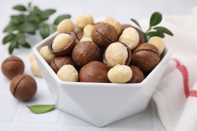 Photo of Tasty Macadamia nuts in bowl on white table, closeup