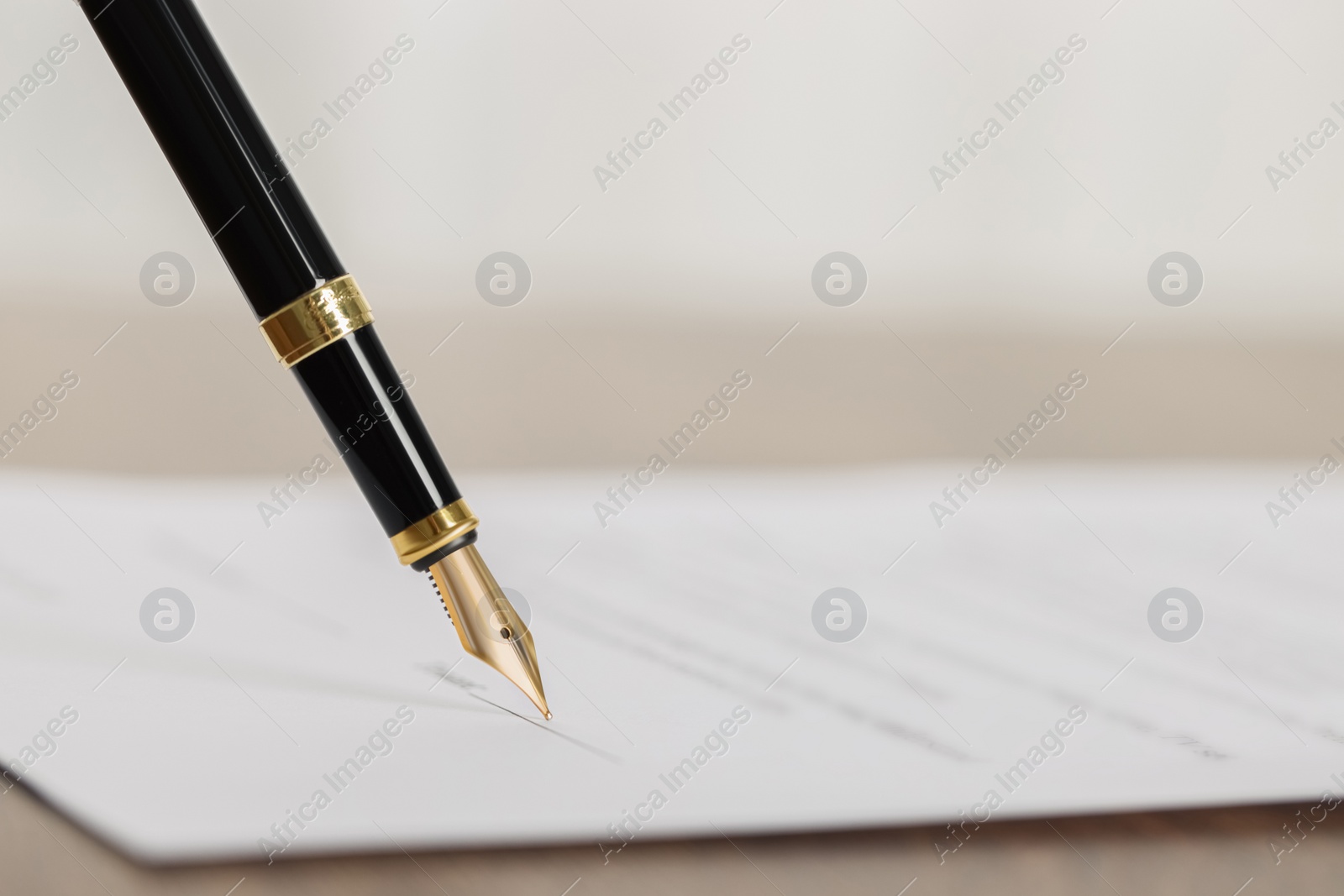 Photo of Writing on document with fountain pen at wooden table, closeup and space for text. Notary contract