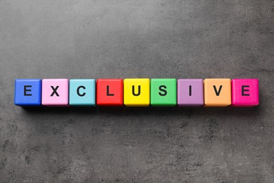 Colorful cubes with word Exclusive on dark grey background, flat lay