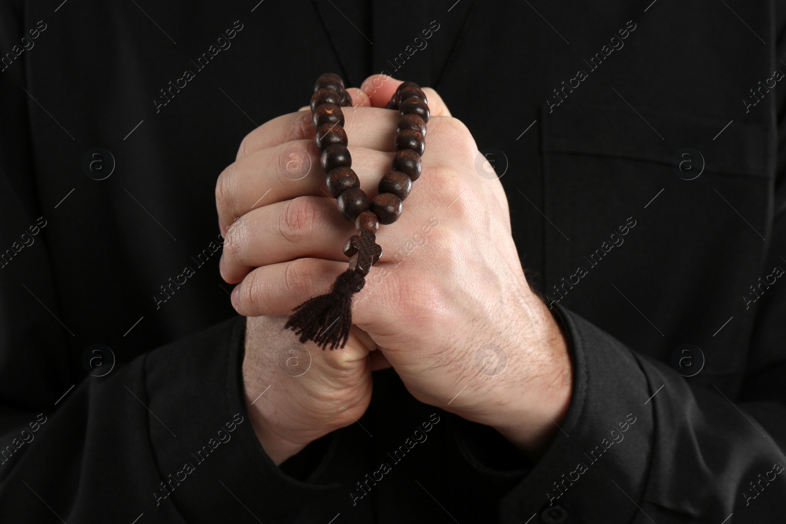 Photo of Priest in cassock with beads praying, closeup