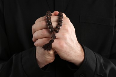 Photo of Priest in cassock with beads praying, closeup