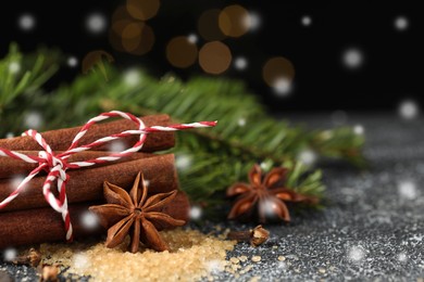 Different spices and fir tree branches on wooden table, closeup. Cinnamon, anise, cloves