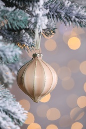 Photo of Christmas tree decorated with holiday bauble against blurred lights, closeup