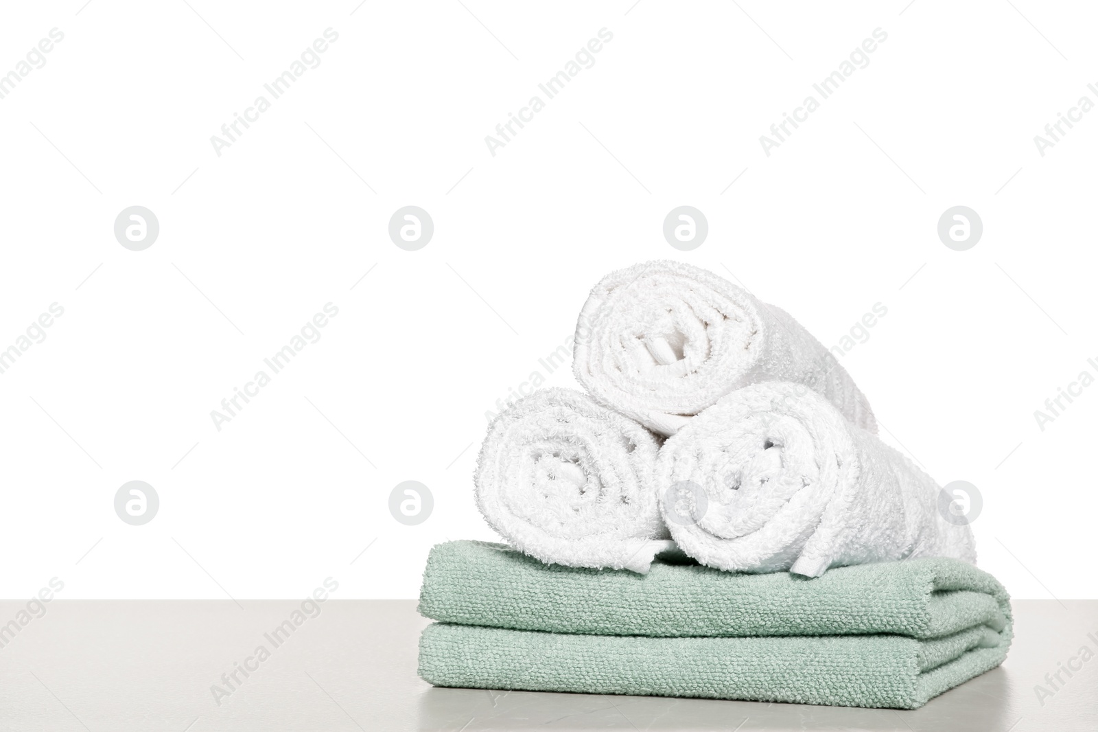 Photo of Soft colorful terry towels on light table against white background